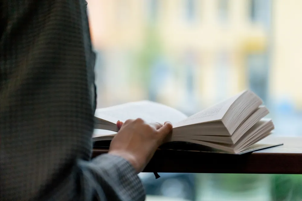 Close,Up,Hand,Hold,Book,In,Bookstore,Near,The,Window